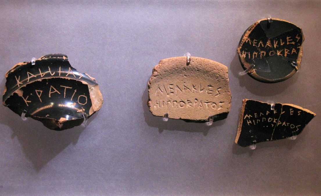 broken shards of pottery with names in greek inscribed into them.